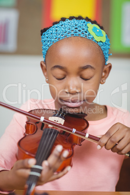 Focused pupil playing violin in a classroom