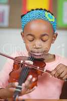 Focused pupil playing violin in a classroom