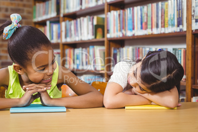 Smiling pupils leaning on books in the library