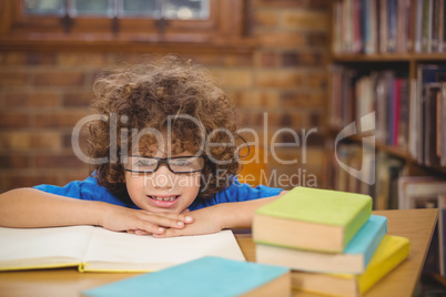 Cute pupil leaning on books in the library