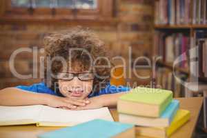 Cute pupil leaning on books in the library