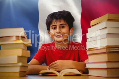Composite image of portrait of boy reading book at desk