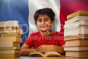 Composite image of portrait of boy reading book at desk