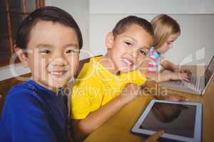 Cute pupils in class using laptop and tablet