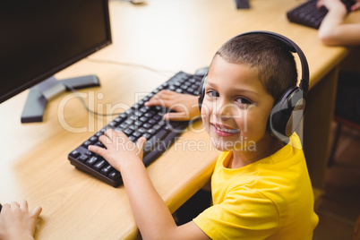 Cute pupil in computer class smiling at camera