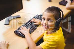 Cute pupil in computer class smiling at camera