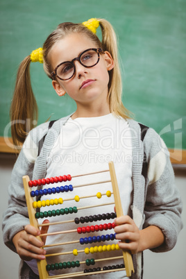 Cute pupil holding abacus in a classroom