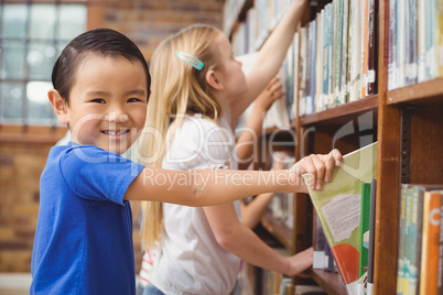 Pupils taking books from shelf in library