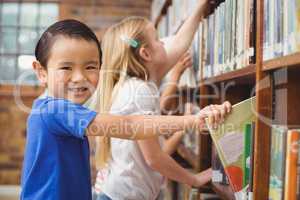 Pupils taking books from shelf in library