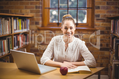 Blonde teacher reading book in the library