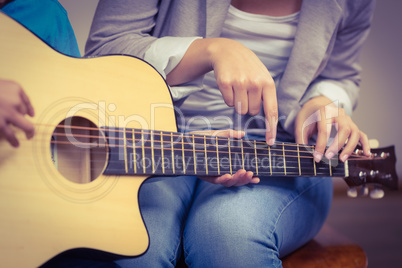 Teacher giving guitar lessons to pupil