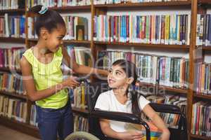 Smiling pupil in wheelchair holding books in the library