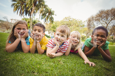 Smiling classmates lying in a row in grass