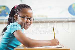 Smiling pupil working at her desk in a classroom