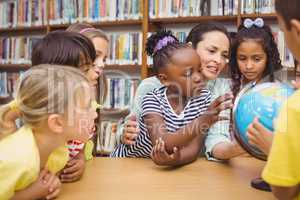 Pupils and teacher looking at globe in library