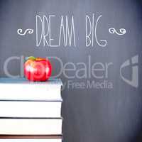 Dream big against red apple in front of blackboard on books