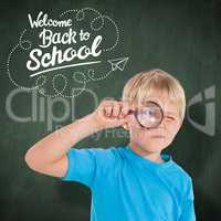 Composite image of cute boy looking through a magnifying glass