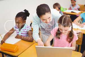 Teacher using laptop with pupil