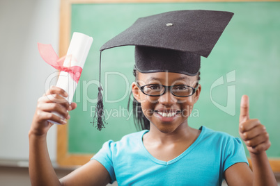 Smiling pupil with mortar board doing thumbs up