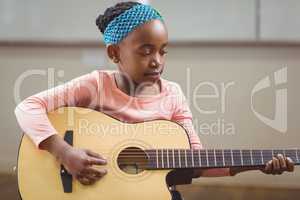Focused pupil playing guitar in a classroom