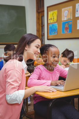 Happy teacher using laptop with student