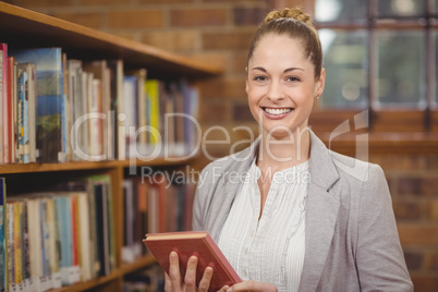 Blonde teacher holding book in the library