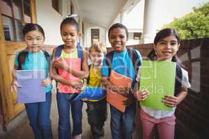 Cute pupils holding notebooks at corridor