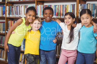 Happy pupils having arms around in the library