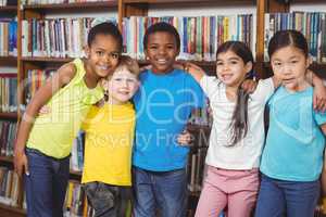 Happy pupils having arms around in the library