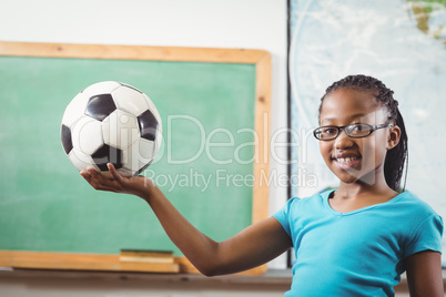 Smiling pupil holding football in a classroom