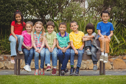 Cute pupils sitting on bench outside