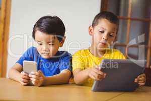 Cute pupils in class using phone and tablet