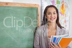 Pretty teacher holding notepads in a classroom