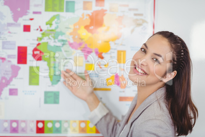 Pretty teacher showing world map in a classroom