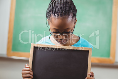 Cute pupil looking down at chalkboard in a classroom