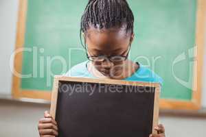 Cute pupil looking down at chalkboard in a classroom