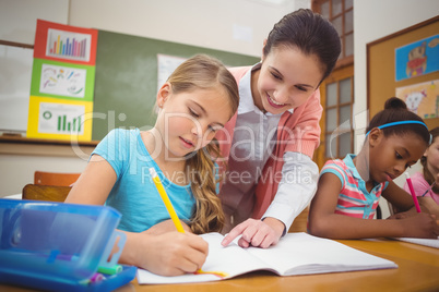 Pupil and teacher at desk in classroom