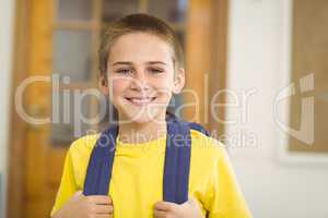 Smiling pupil with schoolbag in a classroom