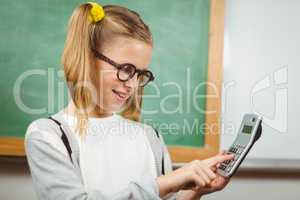 Cute pupil calculating with calculator in a classroom