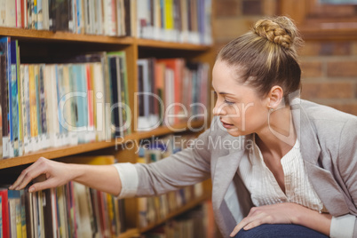 Blonde teacher searching book in the library