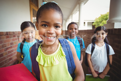 Cute pupils holding notebooks at corridor