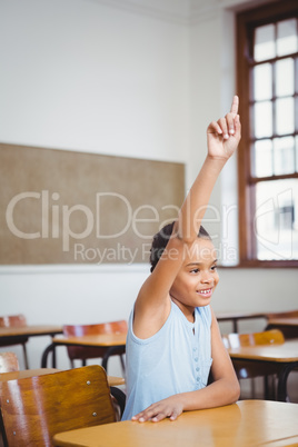 Smiling student sitting at a desk with raised arm