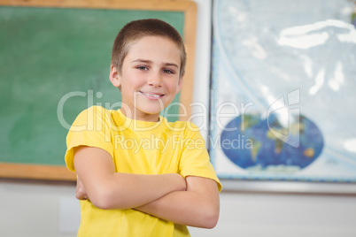 Smiling pupil with arms crossed in a classroom