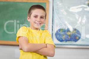 Smiling pupil with arms crossed in a classroom