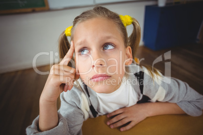 Thoughtful pupil sitting at her desk in a classroom