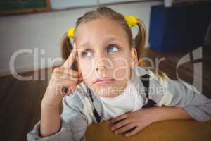 Thoughtful pupil sitting at her desk in a classroom