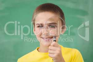 Smiling pupil looking through magnifier in a classroom