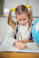 Cute pupil working at her desk in a classroom