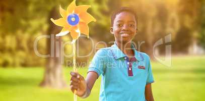 Composite image of happy boy in the park with pinwheel