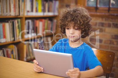 Cute pupil using tablet in the library